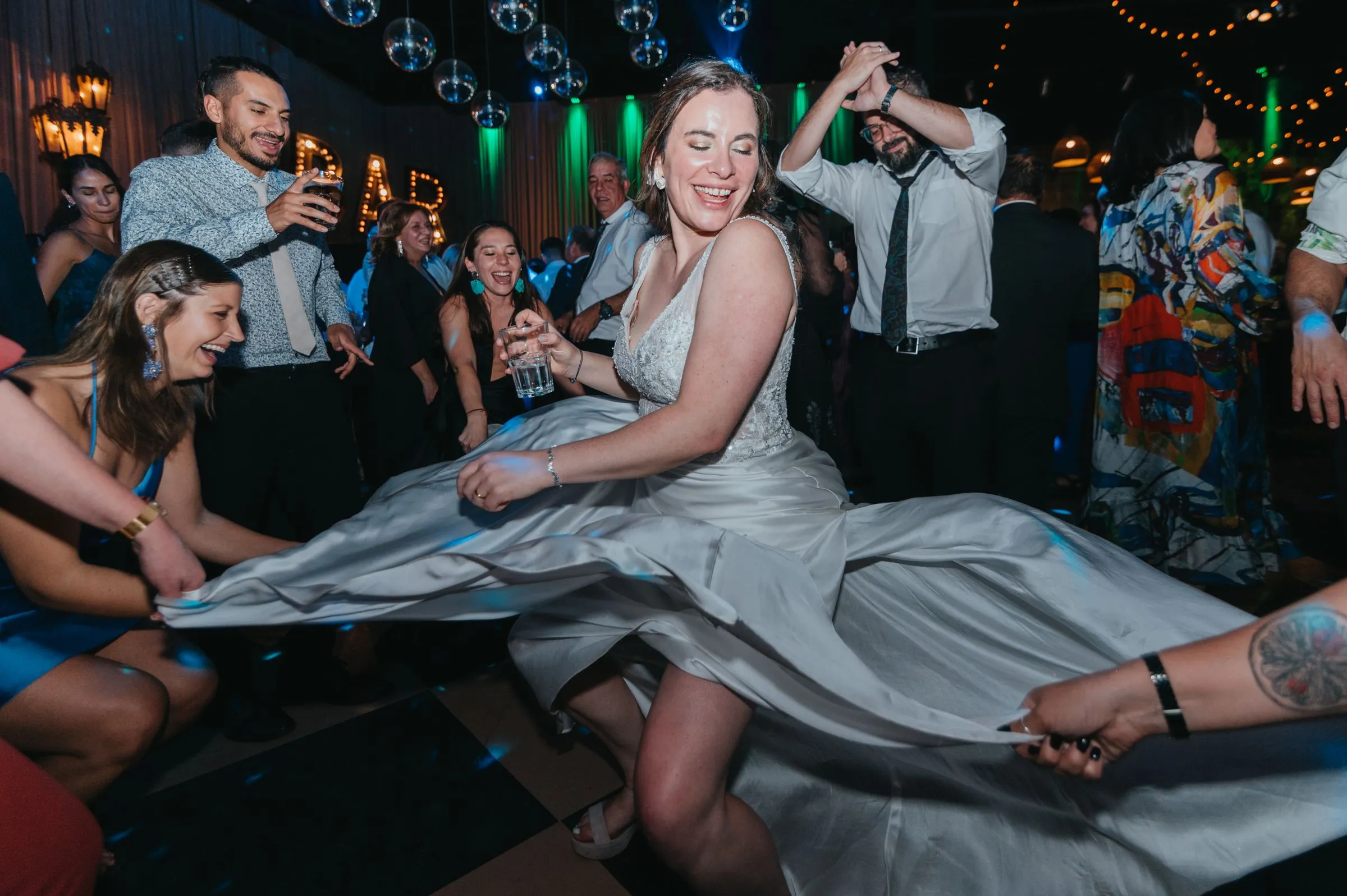 The bride spins on the dance floor with her skirt flying out as friends cheer