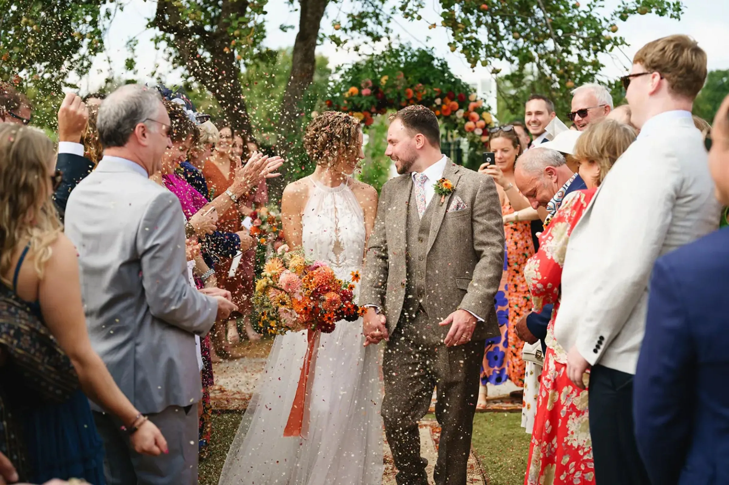 The couple walk back down the aisle through a crowd of guests throwing confetti